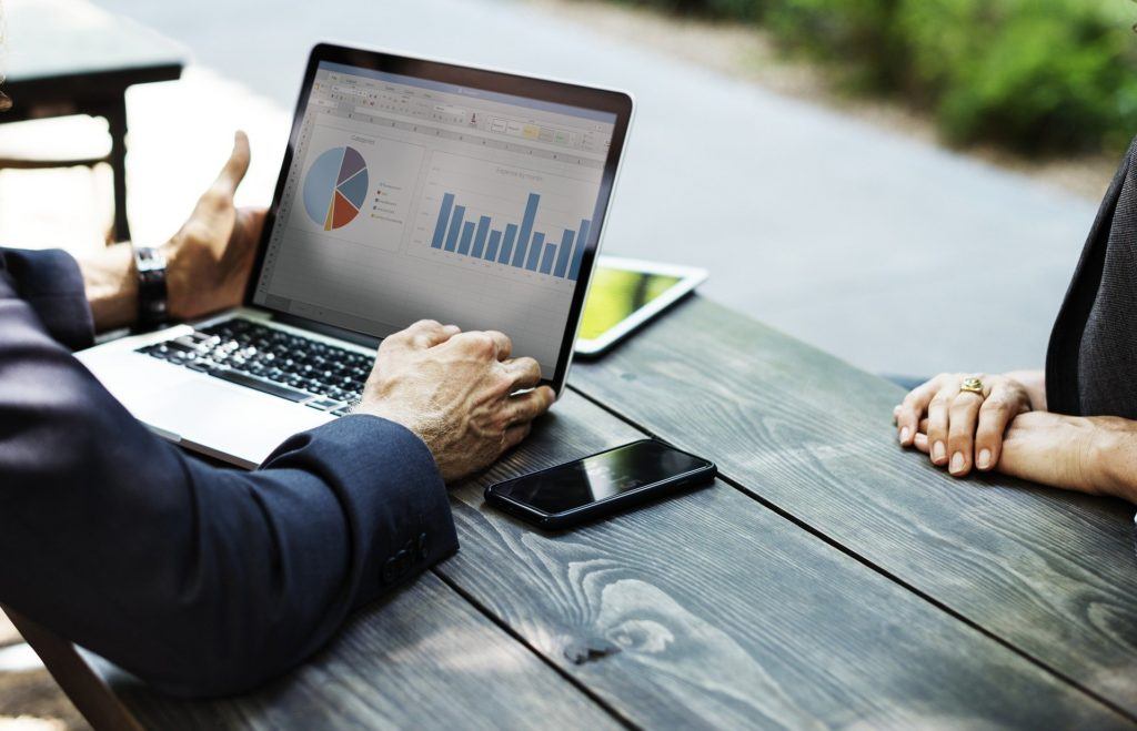 business professionals discuss data analysis in serene outdoor setting with laptop displaying colorful charts. cybersecurity tips.