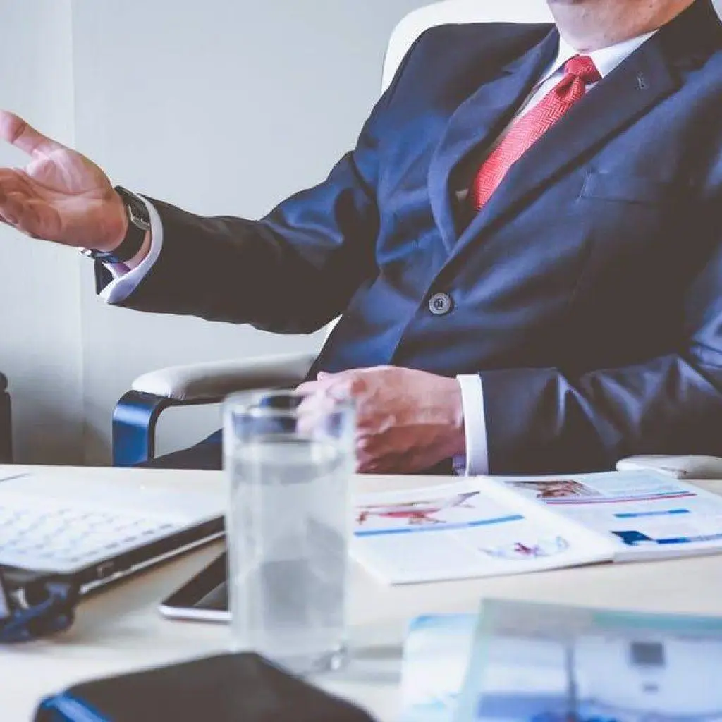 Professional Businessman Discussing Strategy In Modern Office Setting With Laptop, Papers, And Water. Business Owners. professional businessman discussing strategy in modern office setting with laptop, papers, and water. business owners.