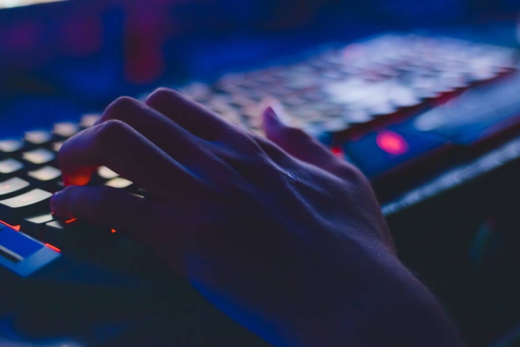 hand on backlit gaming keyboard in moody nighttime setting, ready for action. wireless security.