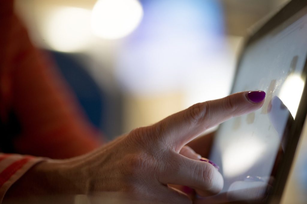 purple nails tapping a tablet in a cozy setting, showcasing modern technology integration. touchscreens.