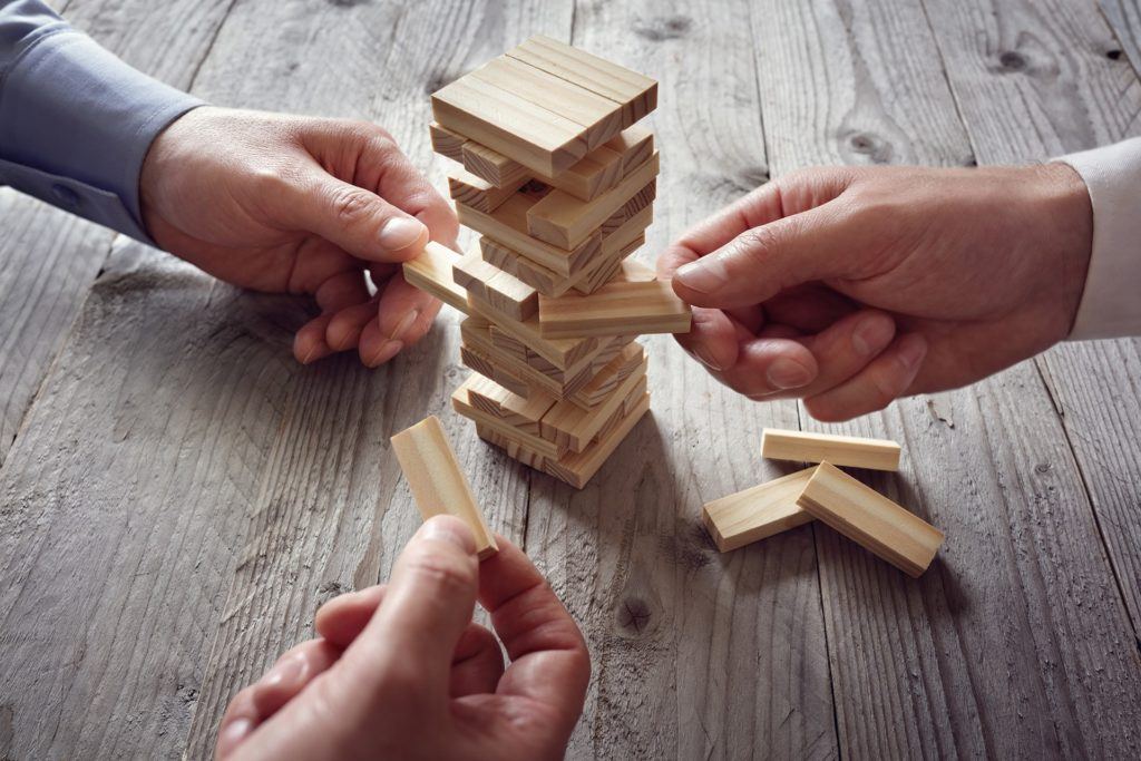 Strategic Jenga game: players carefully remove blocks on rustic tabletop for balance. computing securely.