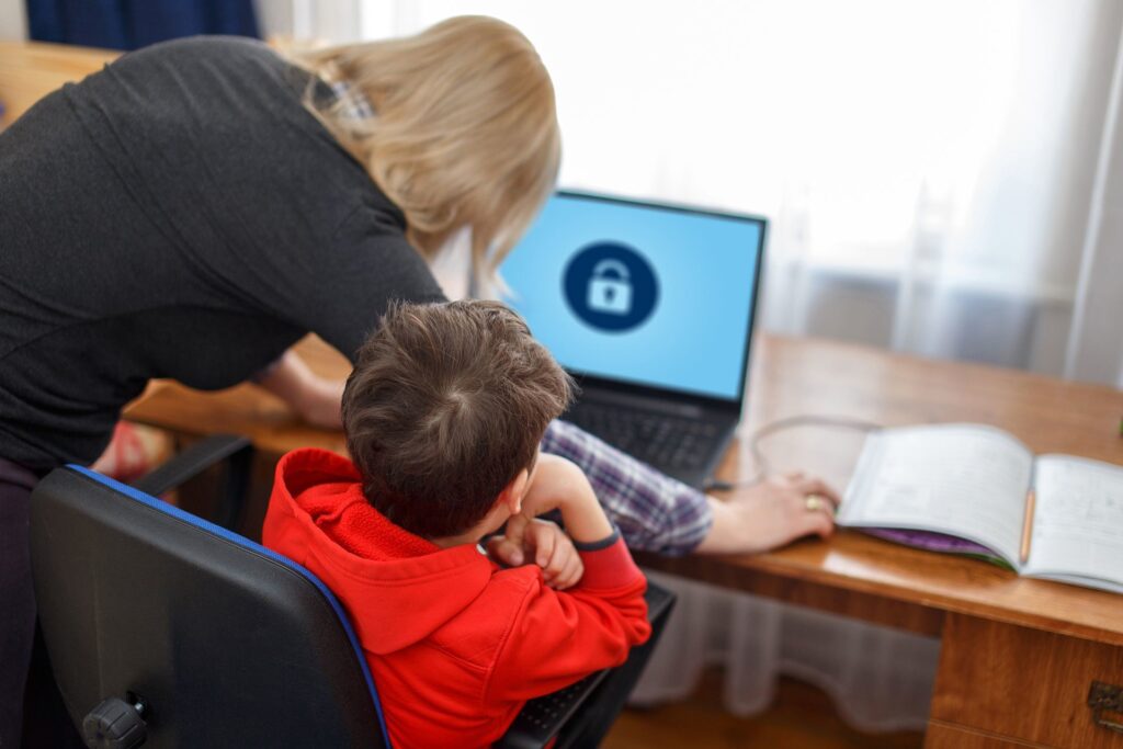 collaborative learning moment: supportive adult assists child with locked laptop in cozy home. keep your kids safe.