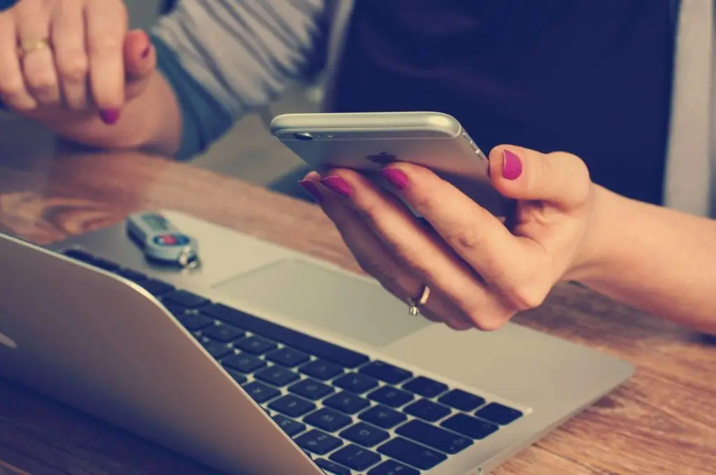 person using smartphone and laptop in stylish and cozy workspace. byod.
