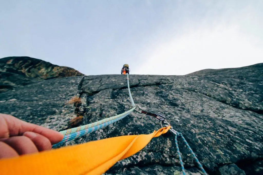 thrilling rock climbing ascent with vibrant safety gear against clear blue sky. security issues.