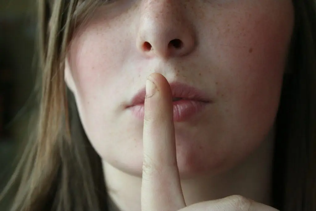 serene portrait of young woman with finger on lips, inviting contemplation. secrets.