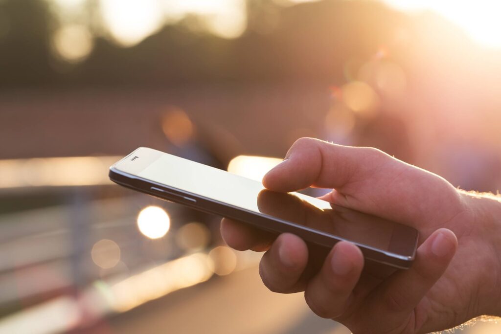 peaceful sunset moment: hand using smartphone outdoors in warm golden light. mobile device management