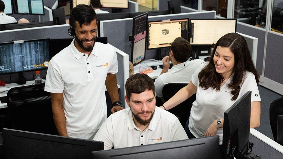 three people working in an office cubicle with computers