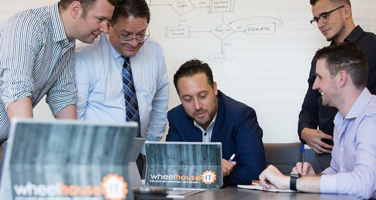 a group of men sitting around a table working on laptops