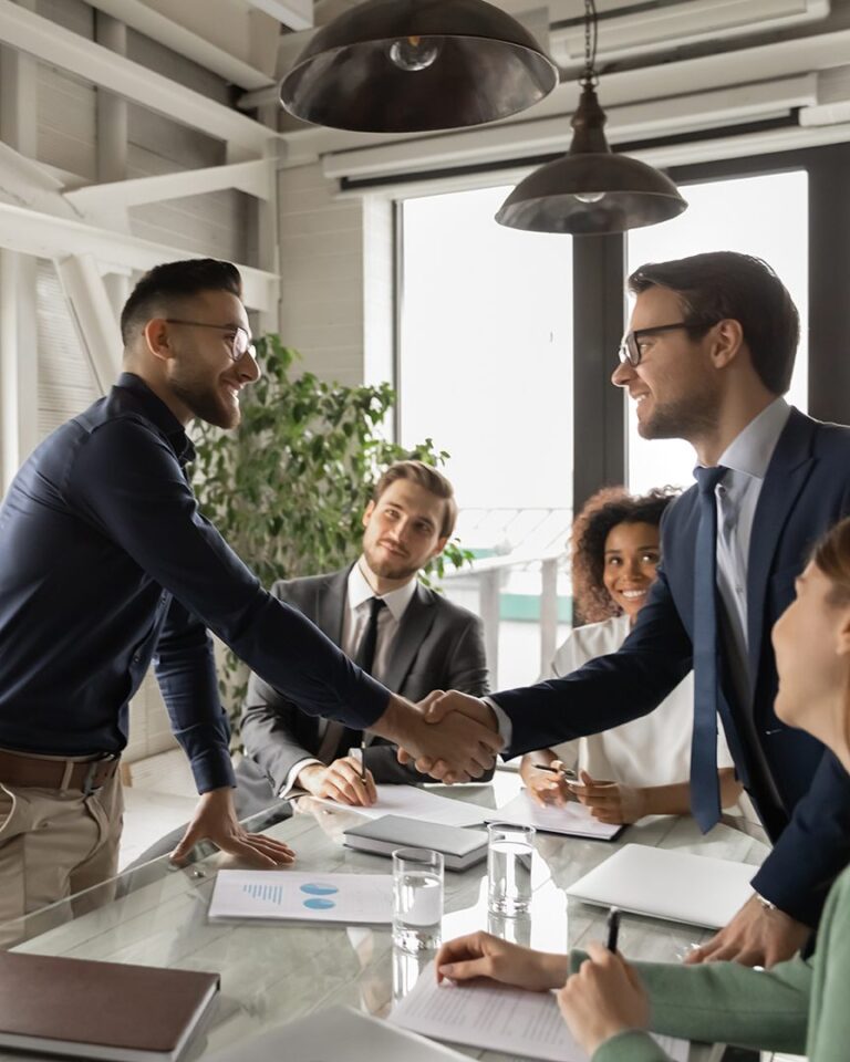 two men shaking hands in front of a group of people