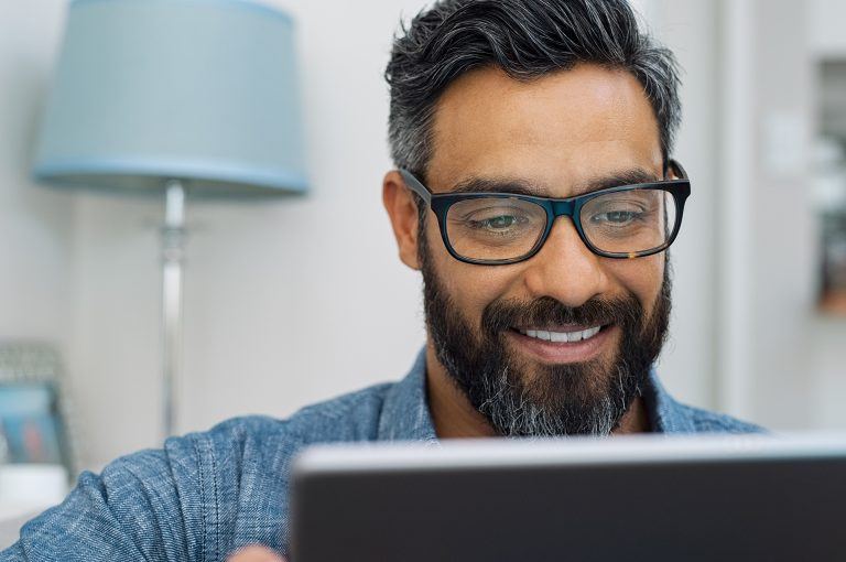 a man wearing glasses looking at a laptop screen