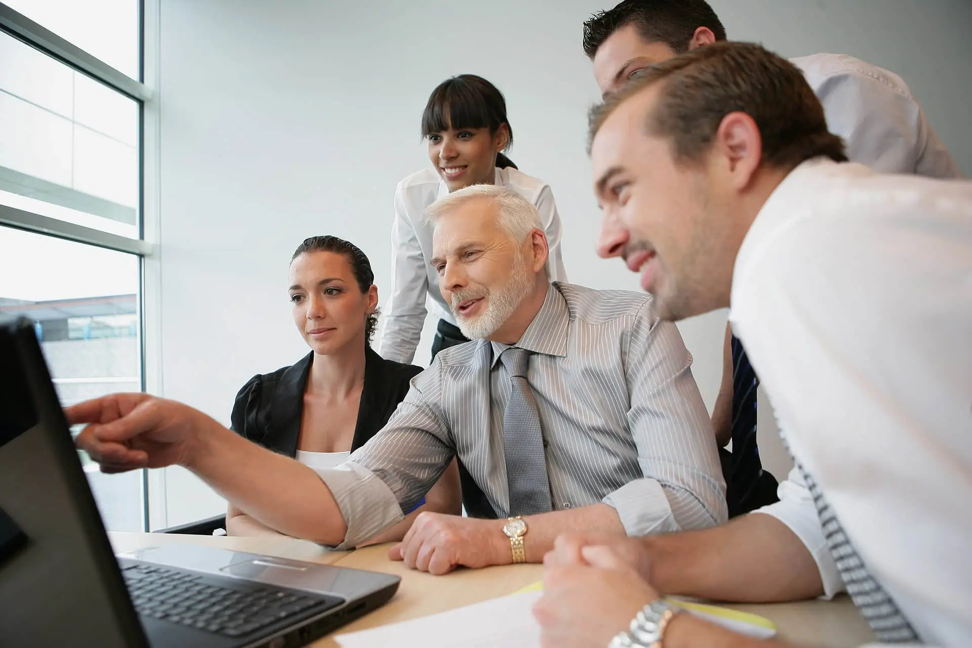 a group of people sitting around a laptop computer