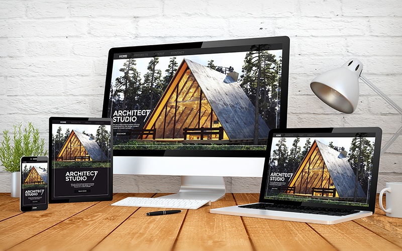 three computer monitors and two laptops on a wooden table