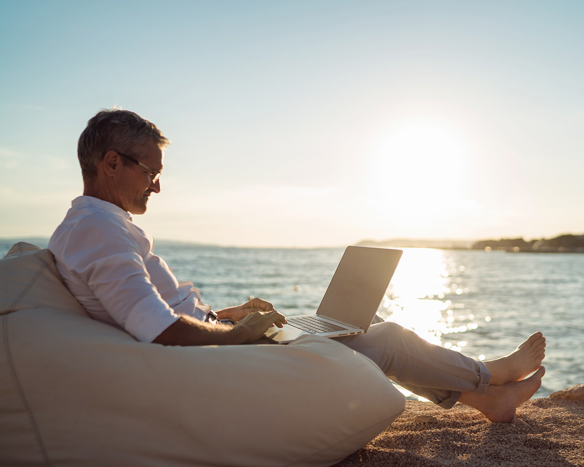 a man sitting on a bean bag chair using a laptop computer