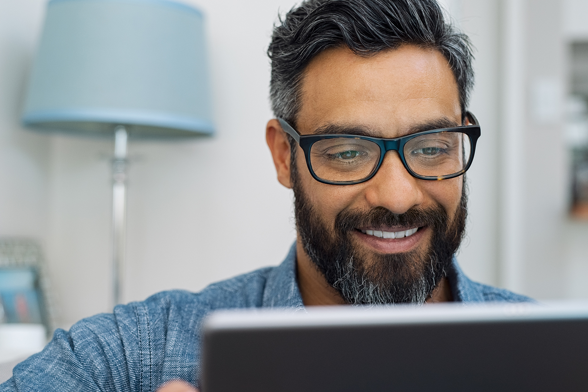 a man wearing glasses looking at a laptop