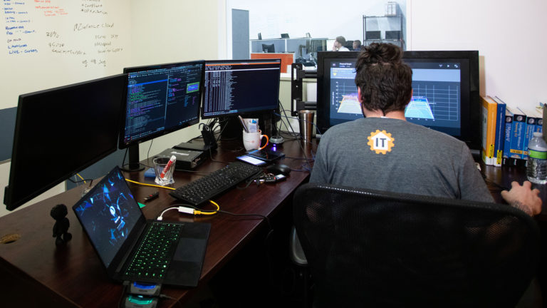 a person sitting at a desk with two monitors