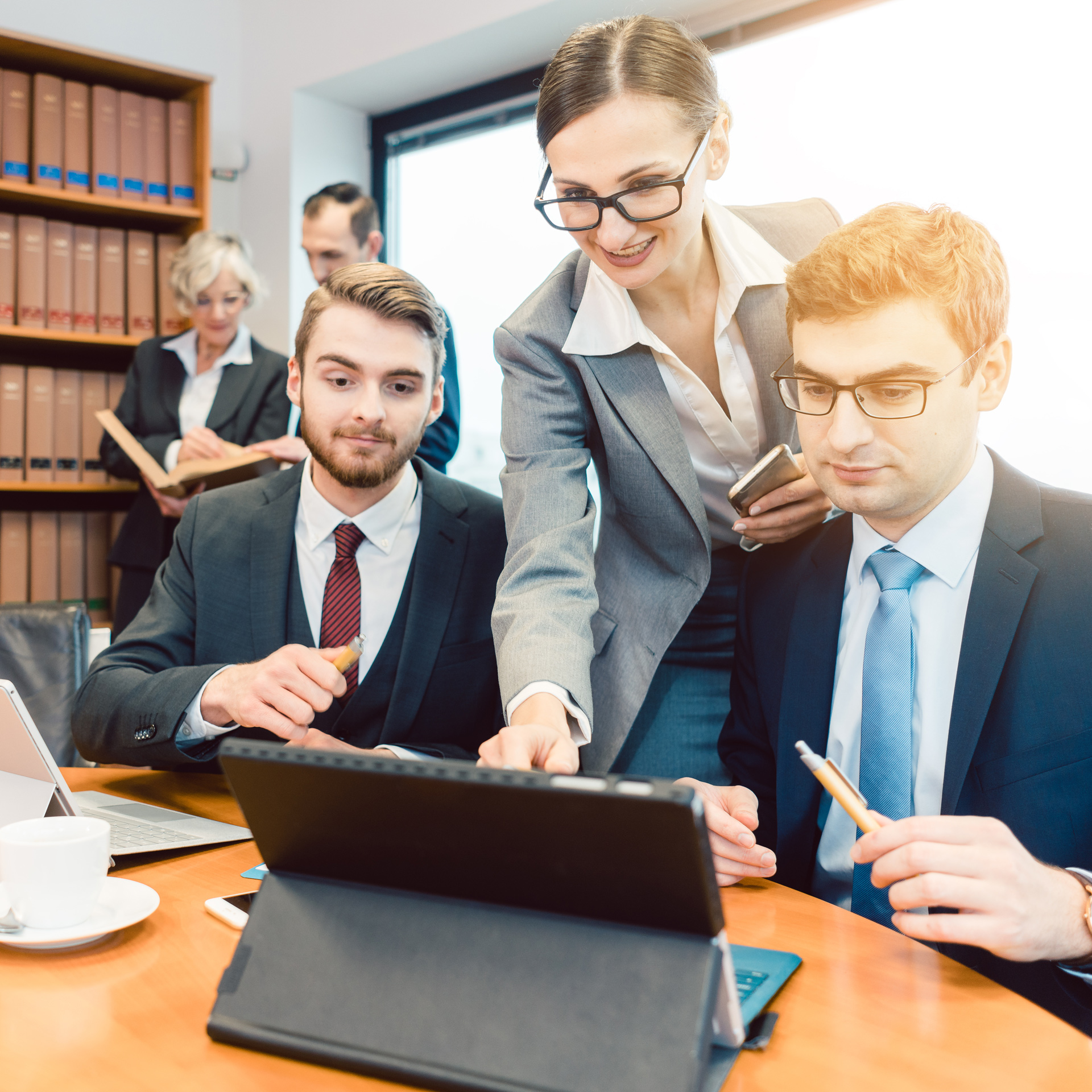 three people in business attire looking at a laptop