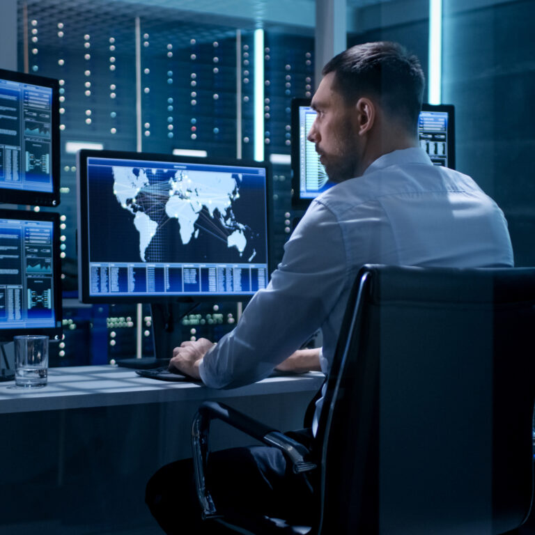 a man sitting at a desk in front of two computer monitors