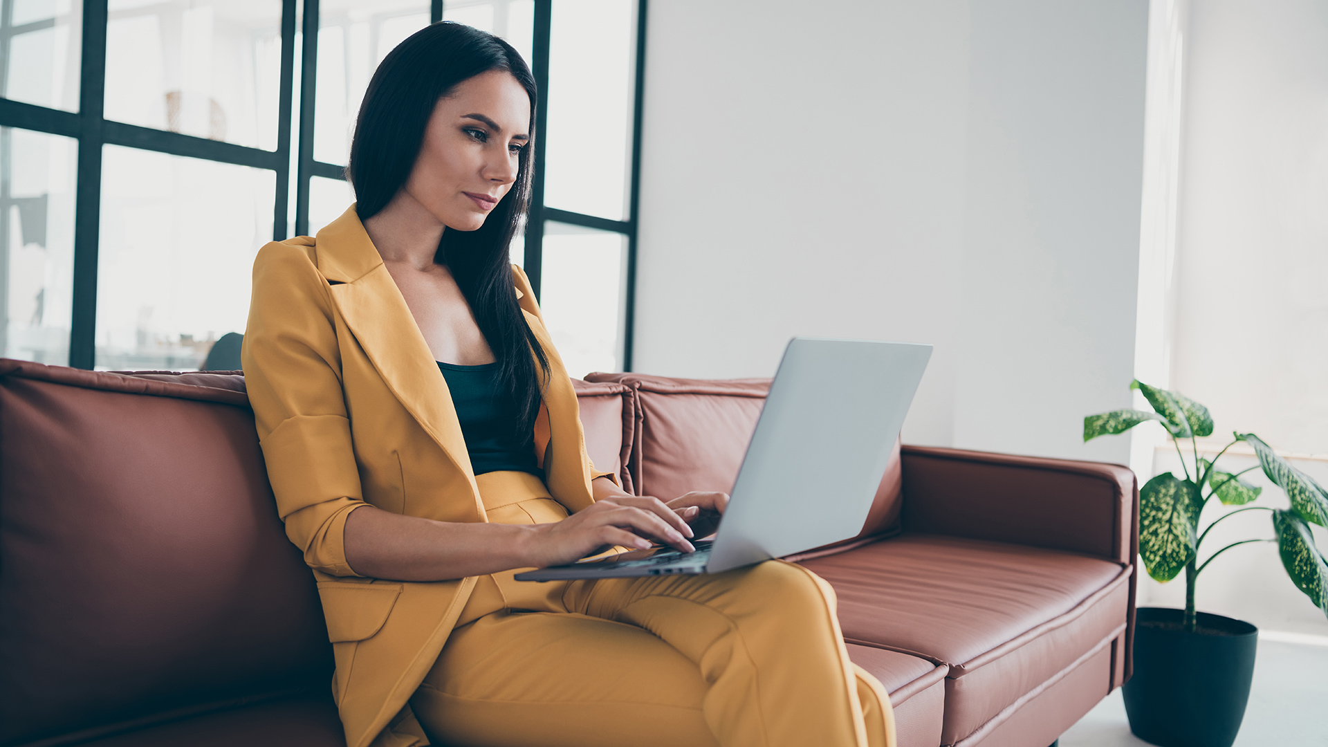 a woman sitting on a couch using a laptop computer