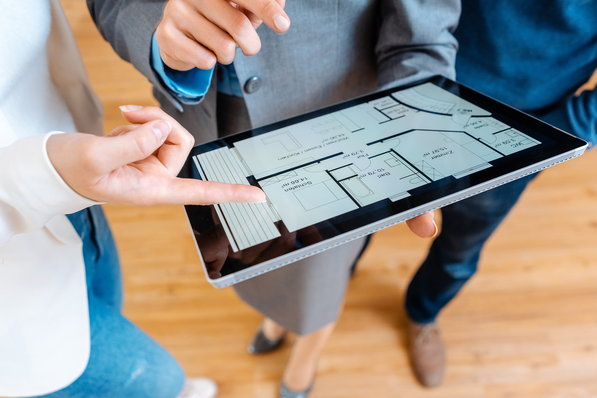 two people holding a tablet with a floor plan on it