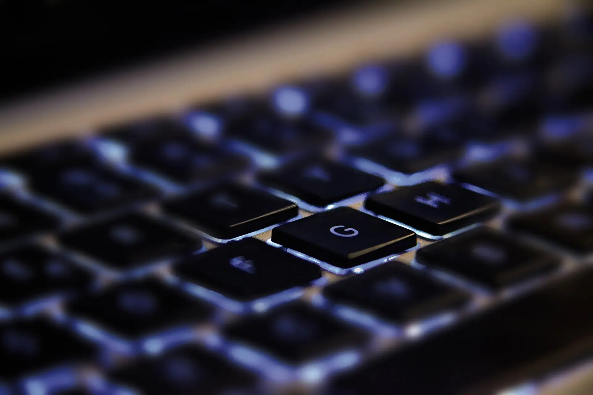Backlit laptop keyboard with glossy keys, highlighting ergonomic design and modern technology.