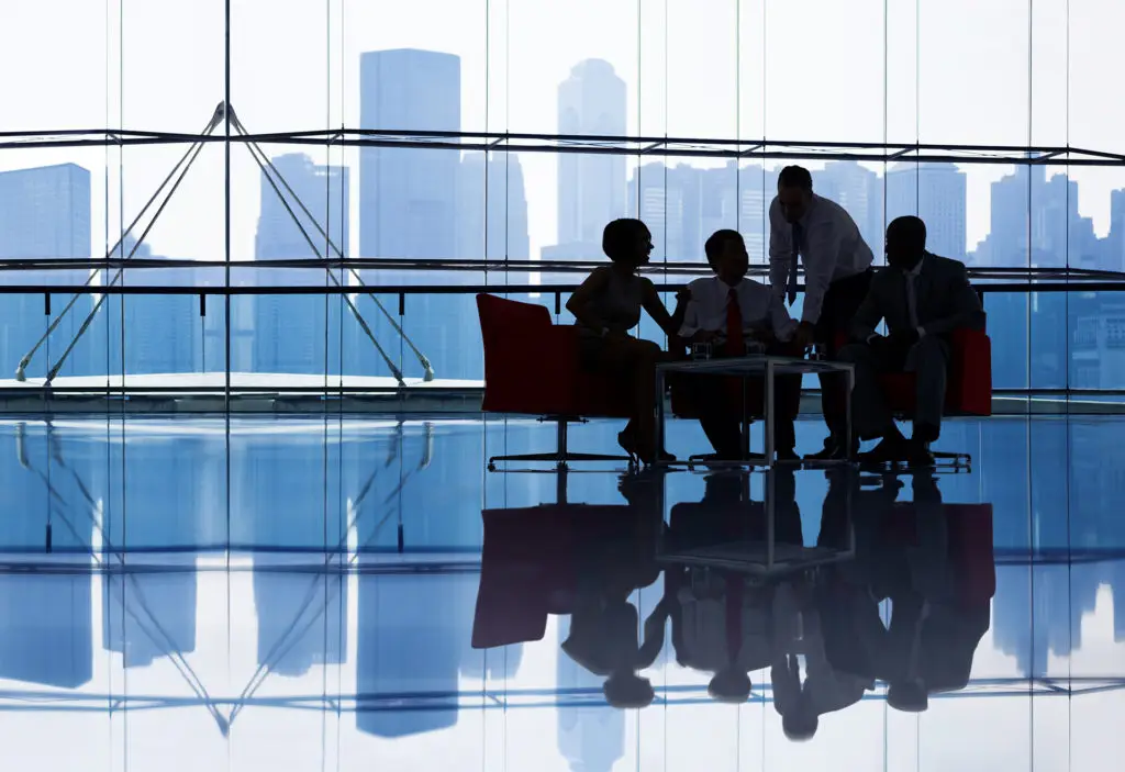 Team Discussing Ideas In Modern Glass Office With City Skyline Backdrop. team discussing ideas in modern glass office with city skyline backdrop.