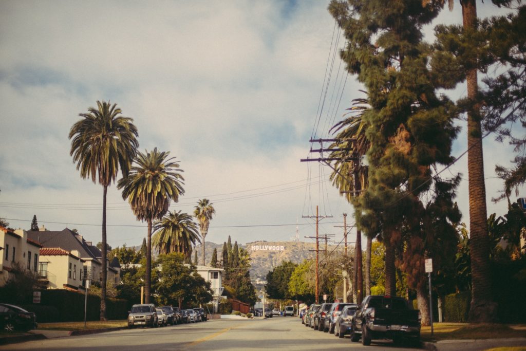 charming suburban street with palm trees, classic homes, cars, and distant hollywood sign.