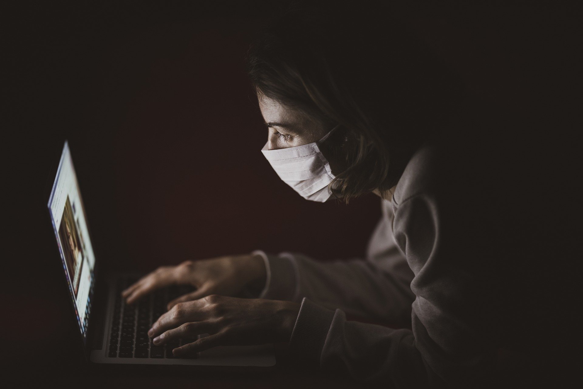 a woman wearing a face mask using a laptop computer