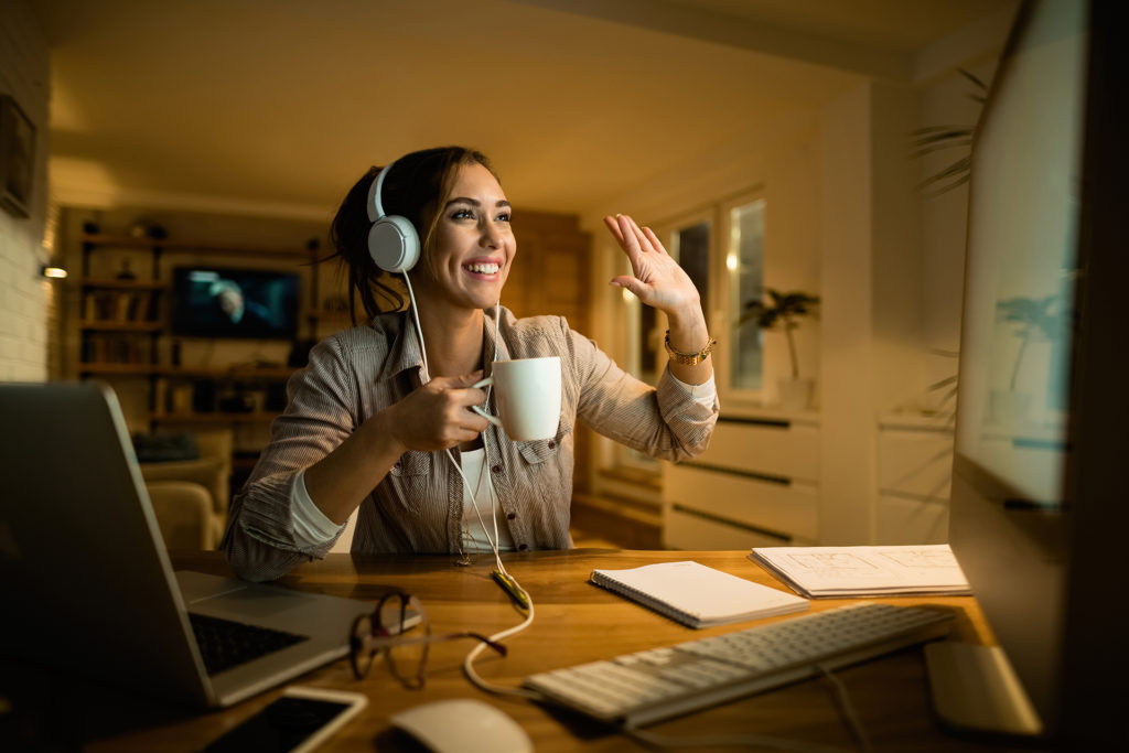 engaged woman in cozy home office video call, smiling warmly.