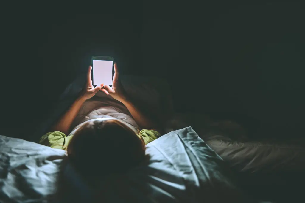 Serene Night Scene: Person In Bed Captivated By Smartphone Glow. serene night scene: person in bed captivated by smartphone glow.