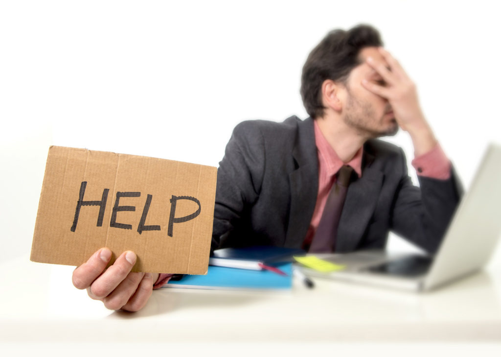 stressed businessman seeking help at chaotic desk, overwhelmed by work demands.