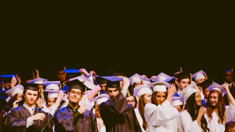 Graduates celebrating milestone achievements in formal attire at graduation ceremony. College