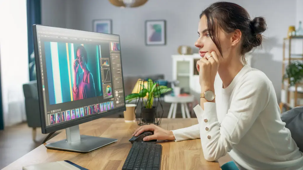focused woman editing vibrant photos in modern, creative workspace with stylish decor.