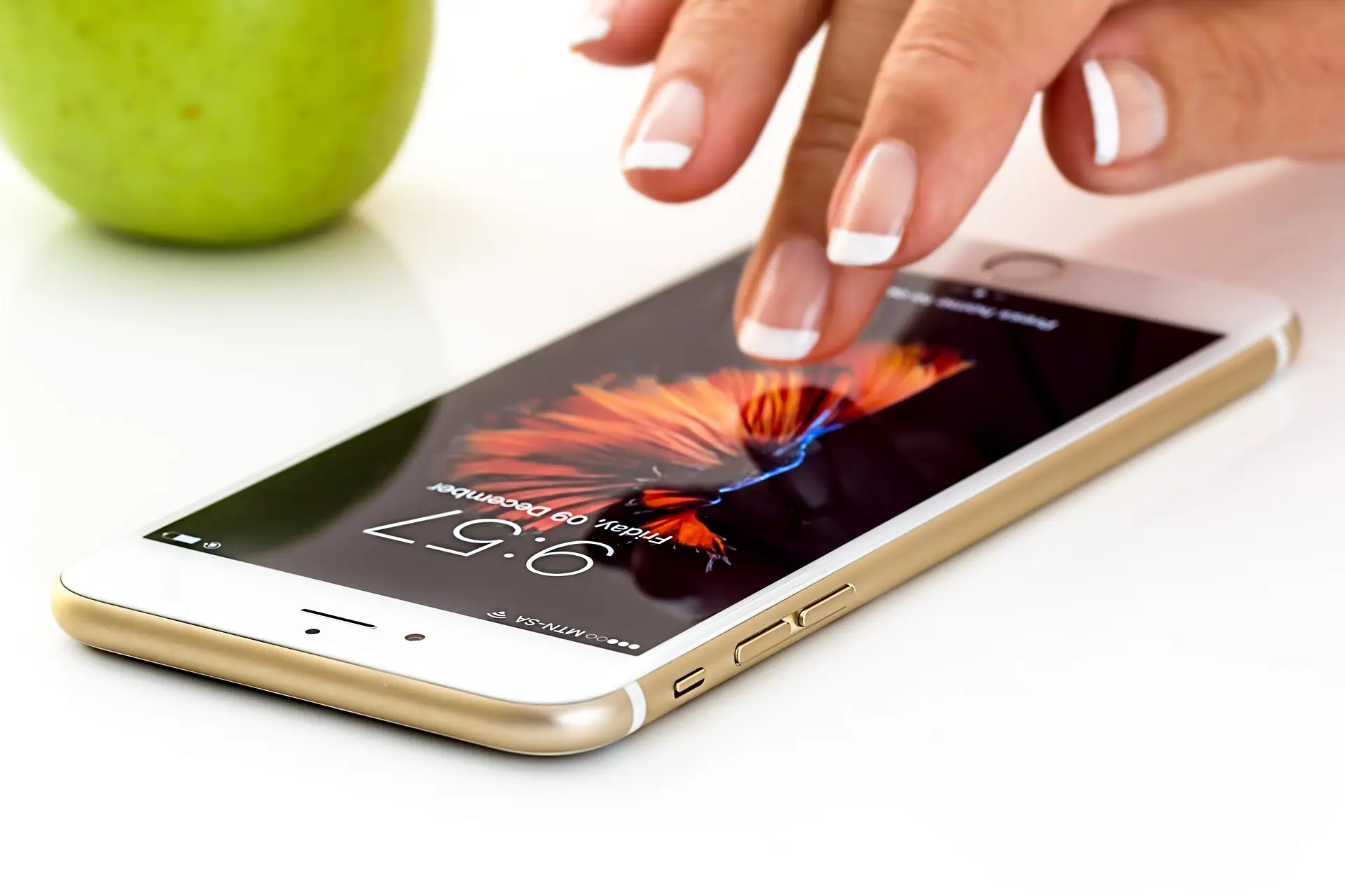 Modern tech meets nature: smartphone touch with green apple on sleek surface.