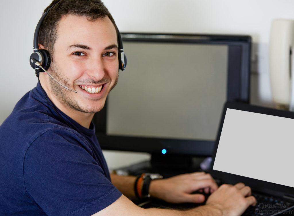 happy man in home office working on laptop with headset, modern and productive environment.