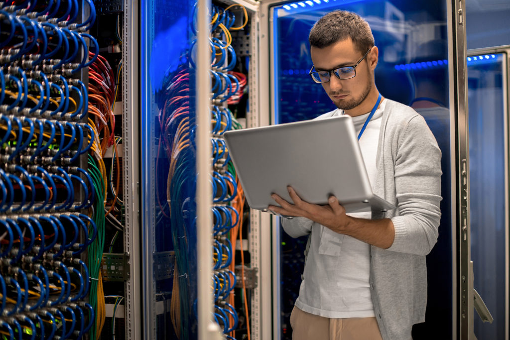 expert it technician managing complex server setup in dimly lit room with blue leds.