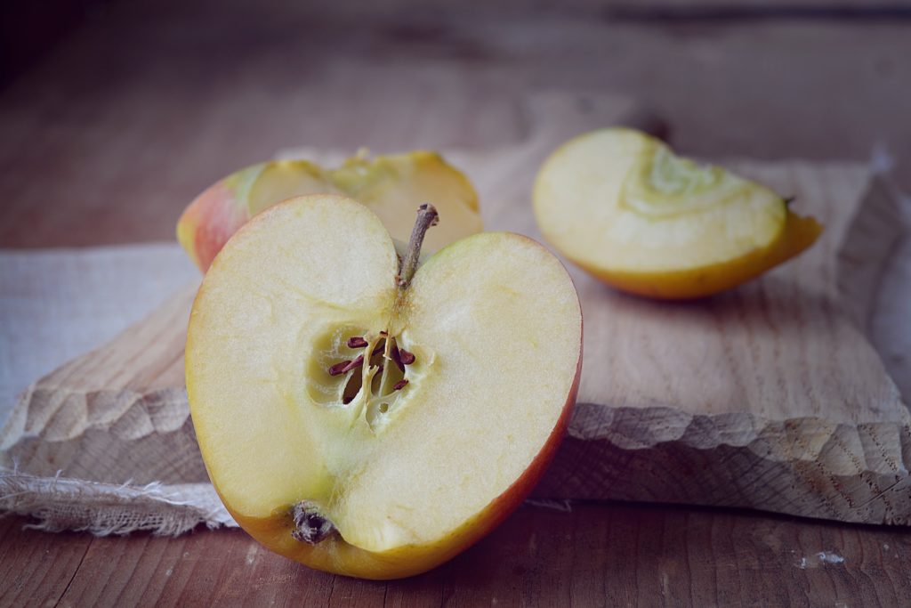 juicy golden apple halves on wooden board, inviting for healthy snacking.