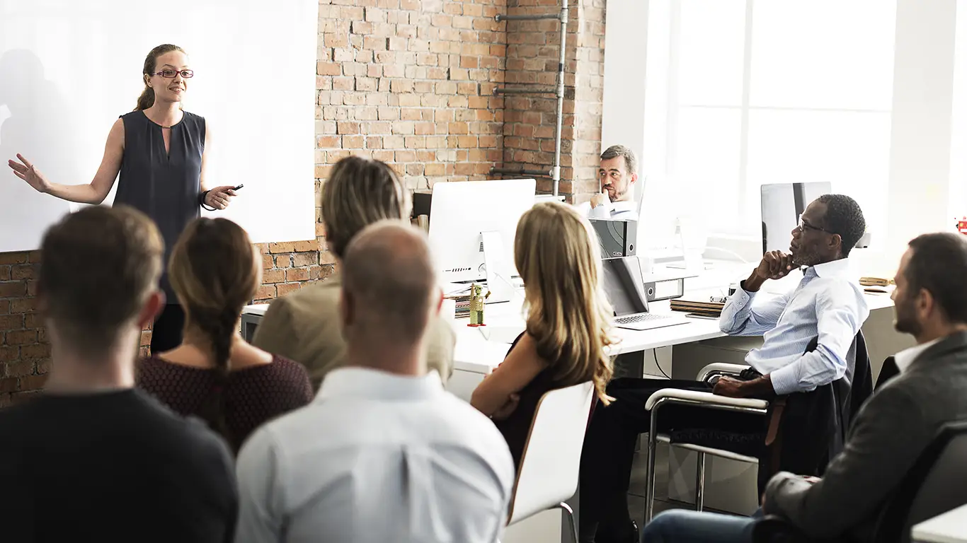 Collaborative office training session with diverse group and confident female speaker.