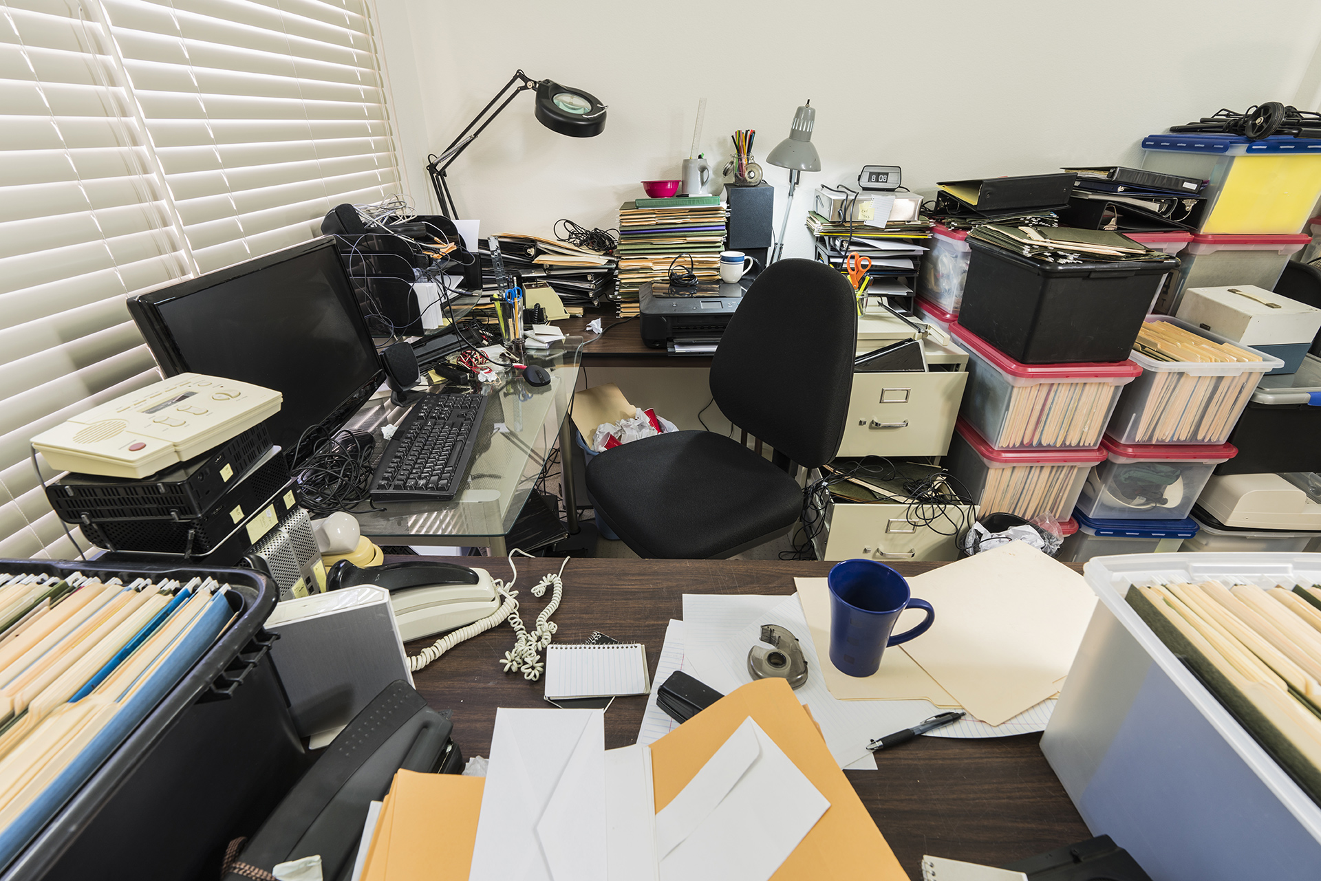 a messy desk with many files and laptops