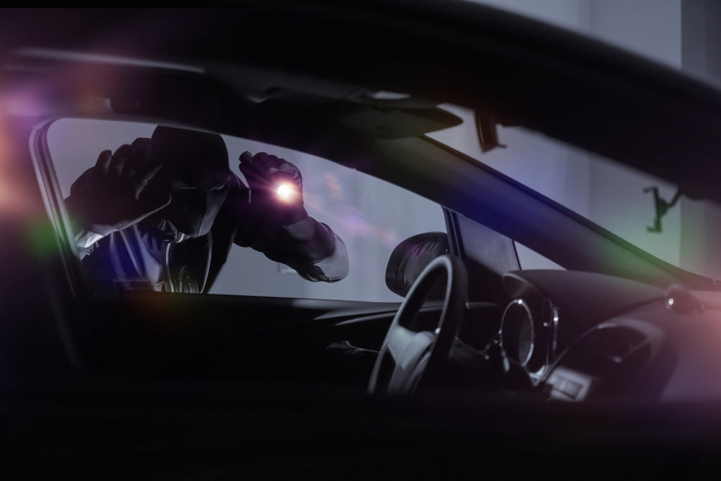 shadowy figure inspecting car interior at night, evoking suspense and mystery.