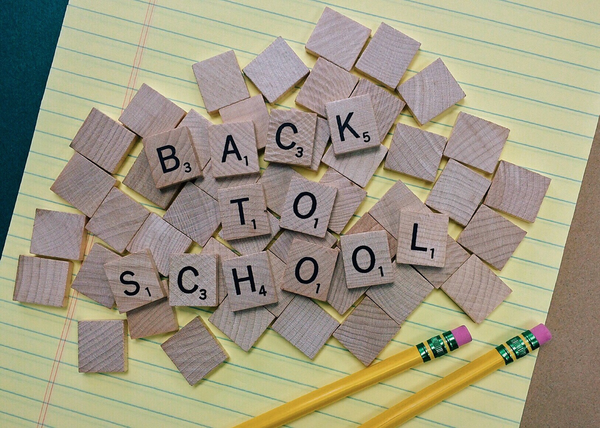 wooden letters spelling back to school on lined paper with pencils