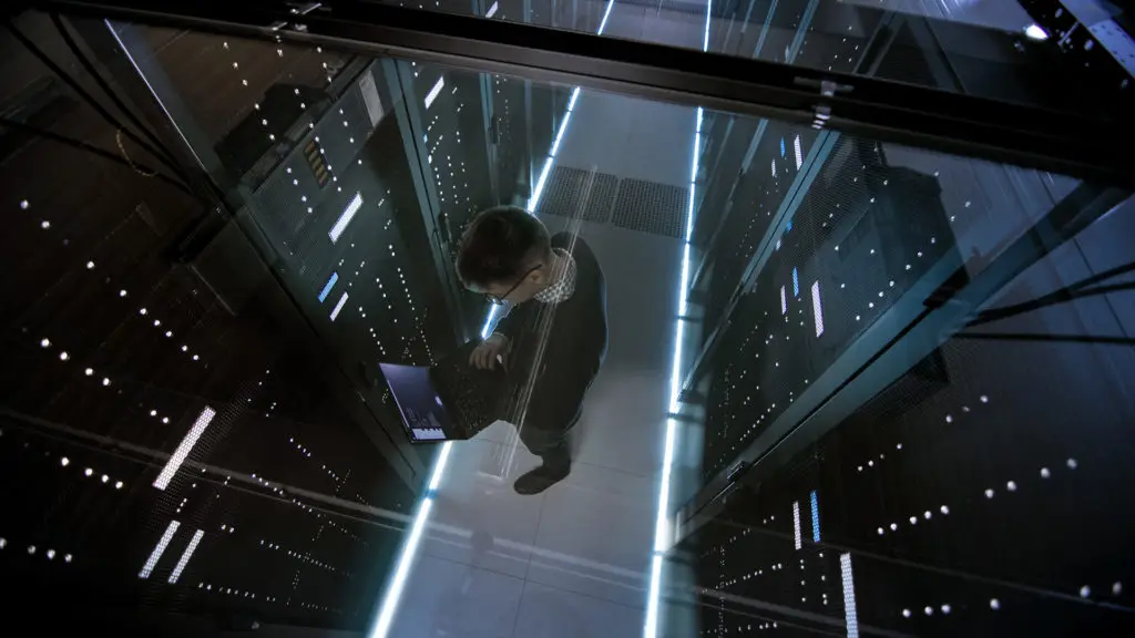human technician monitors servers in high-tech data center environment, showcasing expertise and technology synergy.