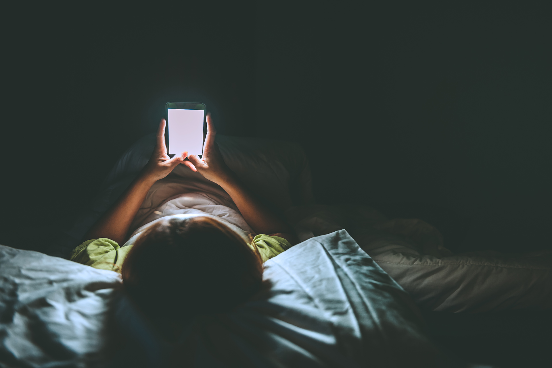 a person laying in bed holding a cell phone