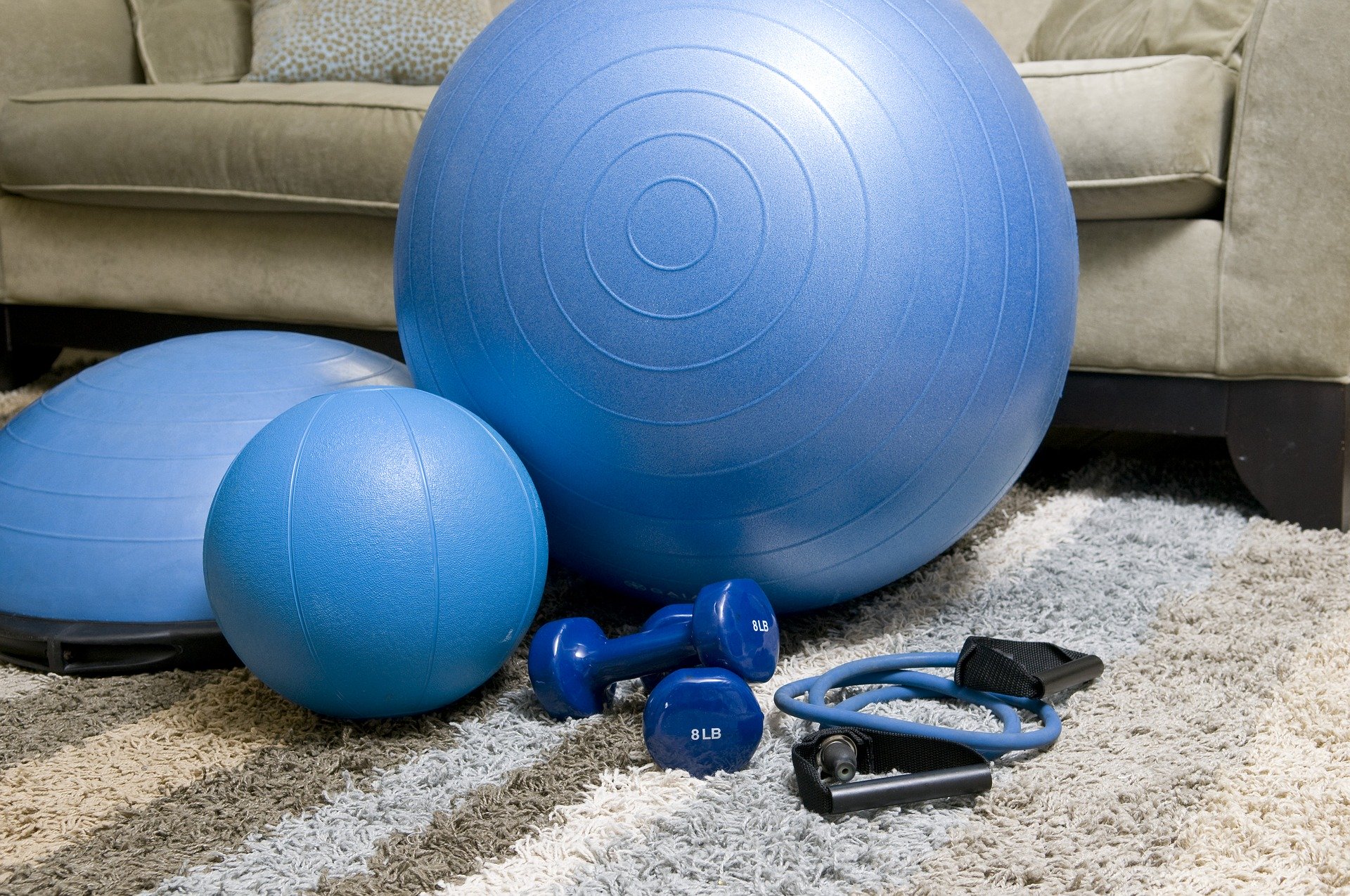 a blue exercise ball, dumbbells, and other equipment on the floor
