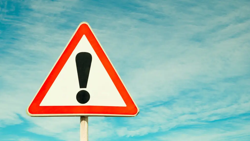 Cautionary Warning Sign Contrasts With Peaceful Blue Sky, Urging Vigilance. cautionary warning sign contrasts with peaceful blue sky, urging vigilance.