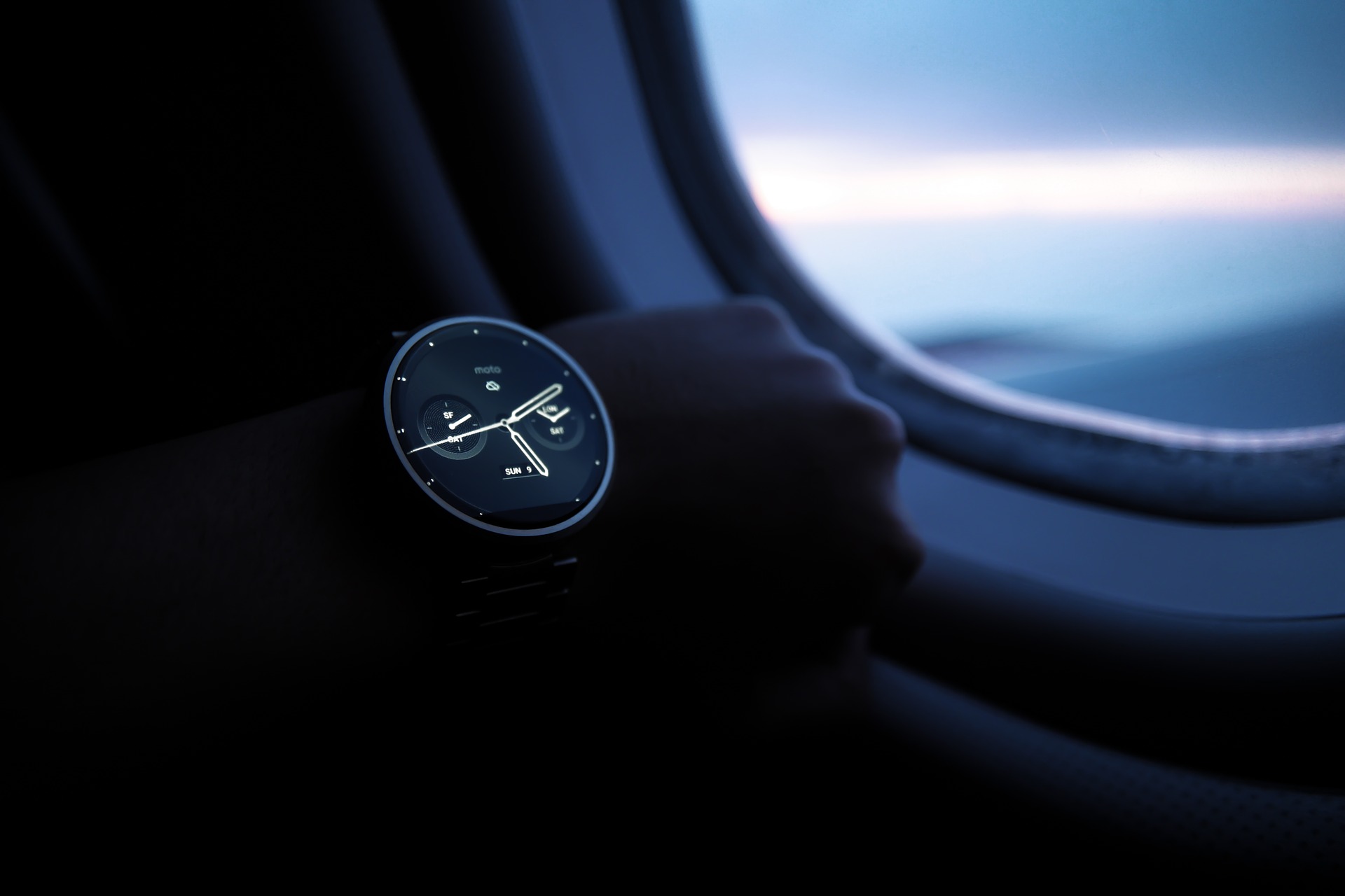 a person holding a watch on their wrist in front of an airplane window