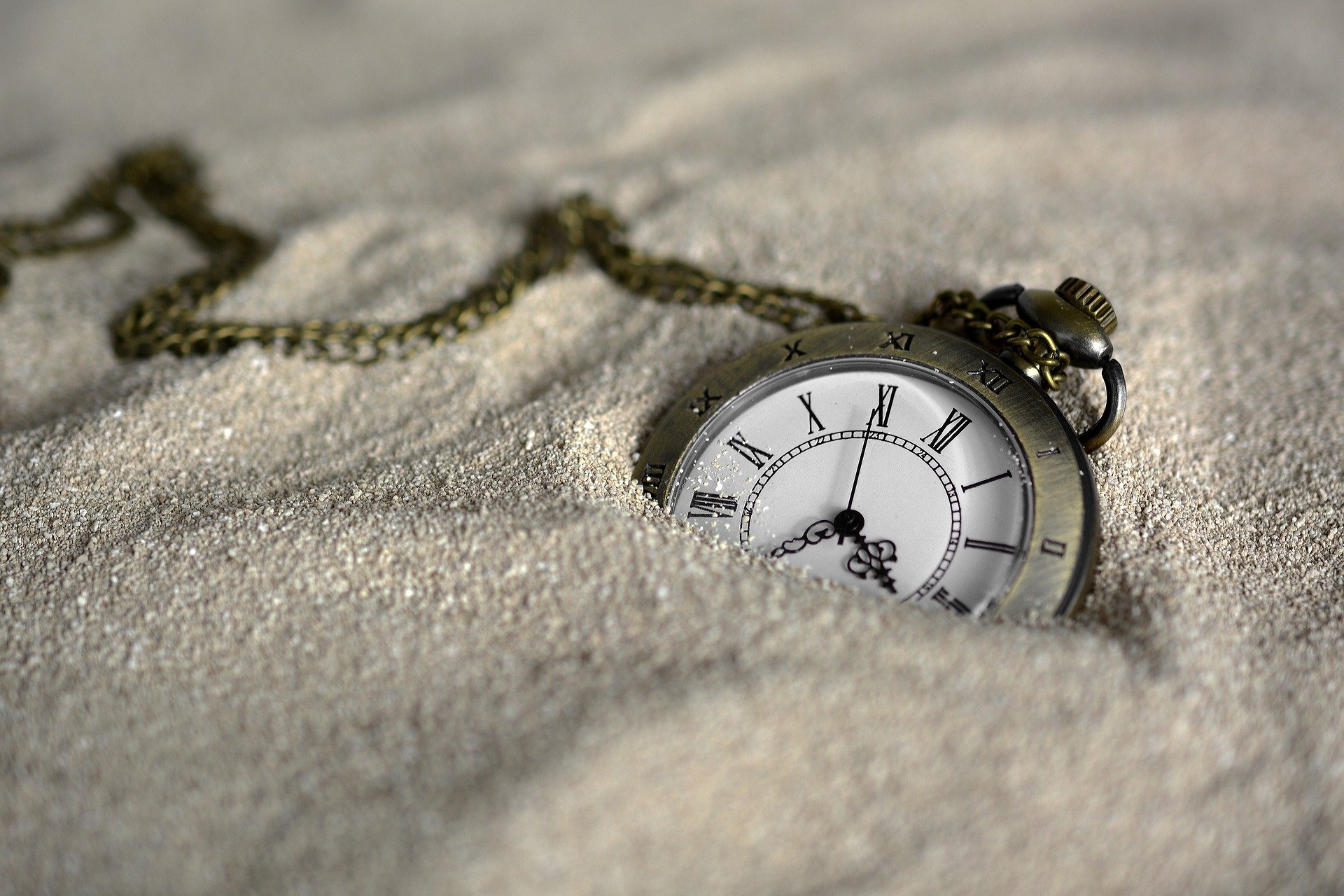 an old pocket watch is laying in the sand
