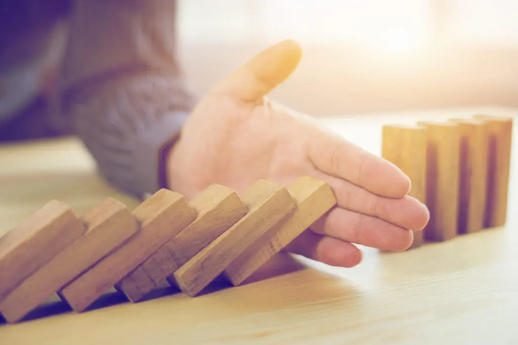 Pause In Motion: Hand Guiding Wooden Blocks, Preventing Cascade, Symbolizing Intervention And Control. pause in motion: hand guiding wooden blocks, preventing cascade, symbolizing intervention and control.