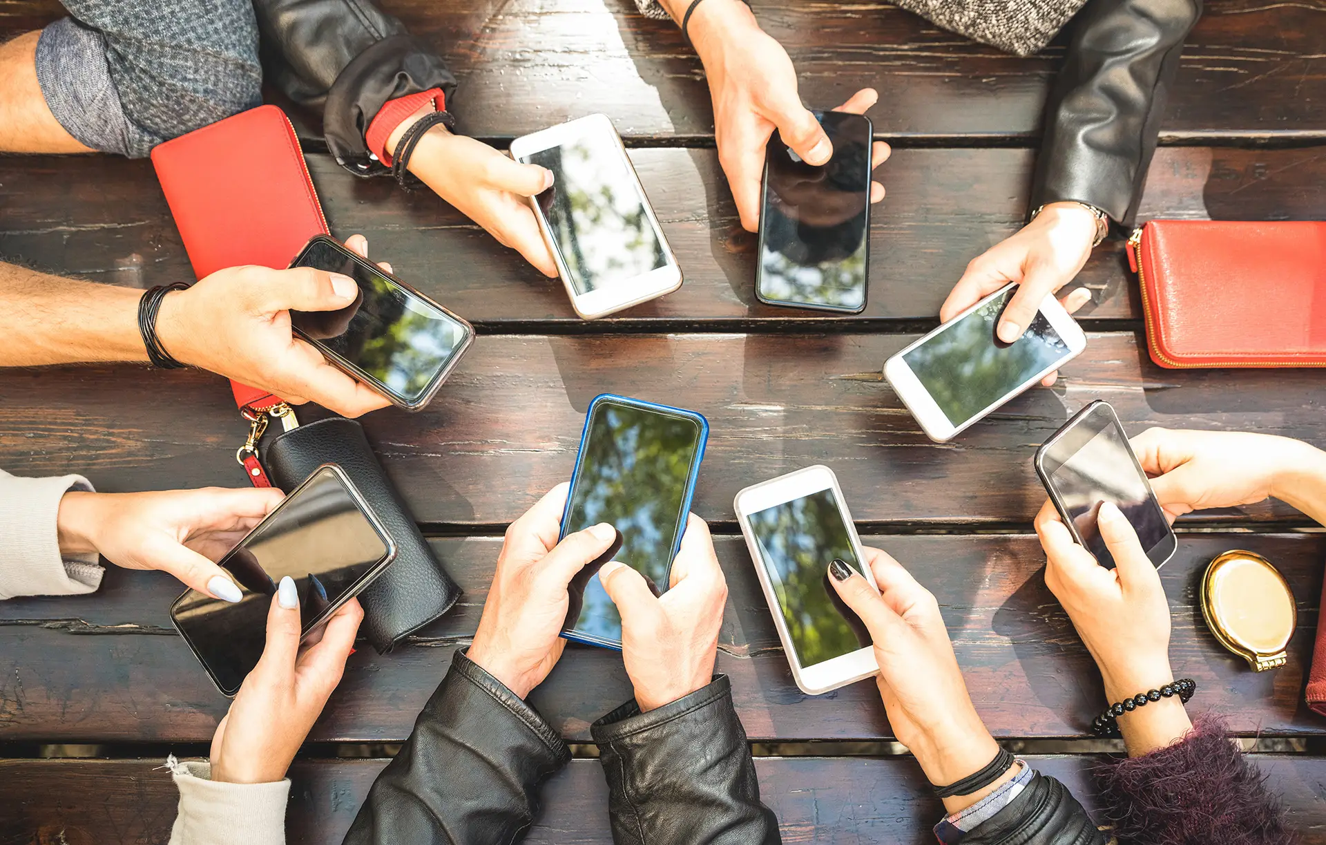 Gathering of friends using smartphones outdoors, reflecting modern social interaction.