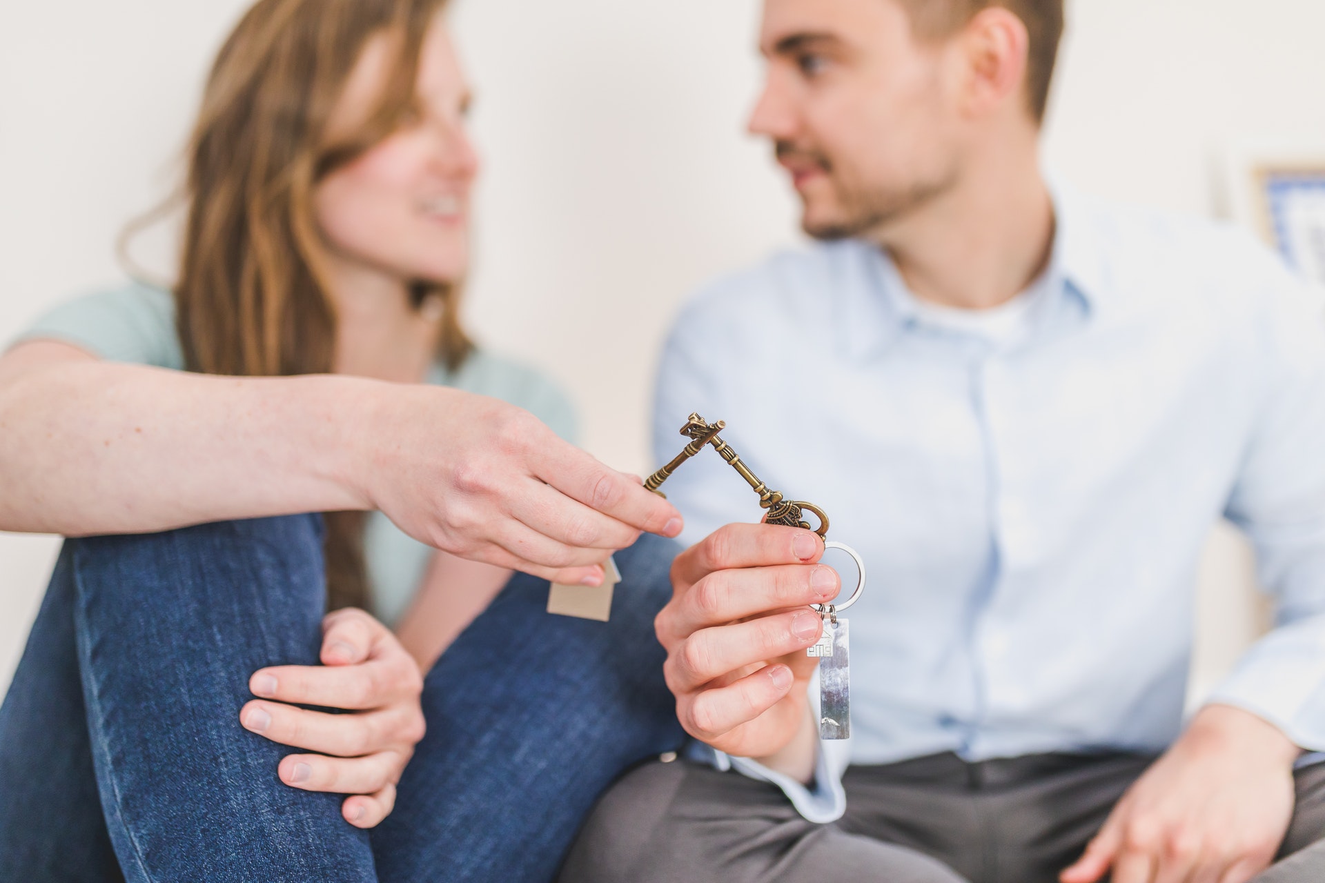 a man and woman sitting on a couch holding keys