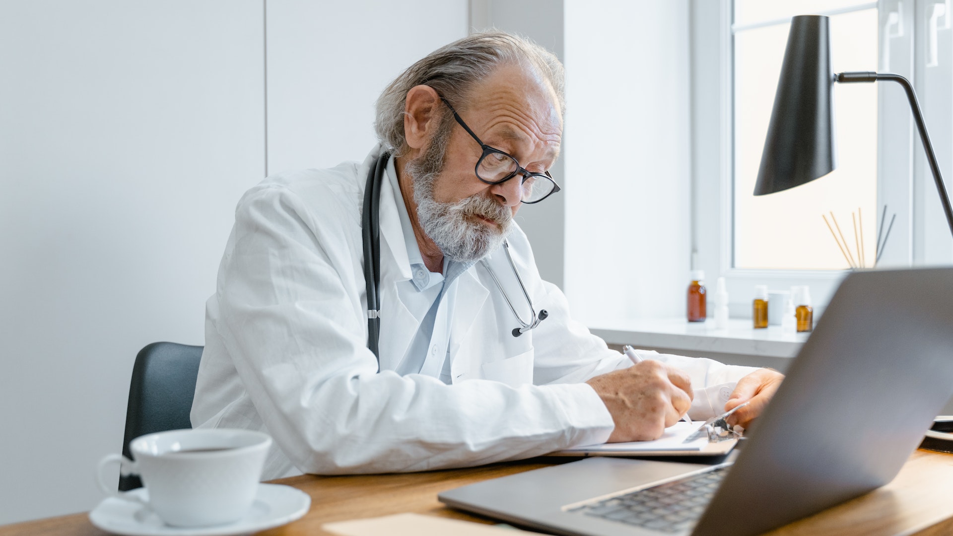 a man with a stethoscope is looking at a laptop